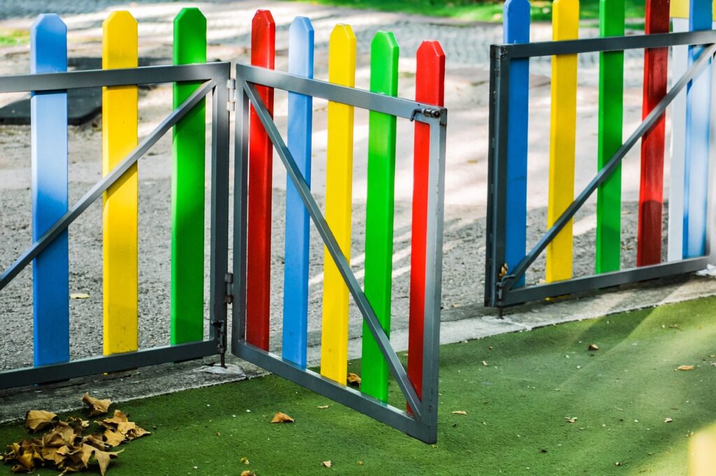 play area, playground, fence, colourful, golden light, sunny, kids, fun, children, play, school yards, school yard fence, kindergarten fence, kindergarten play yard, outsider, nature, leaves, autumn, dried leaves, park gate